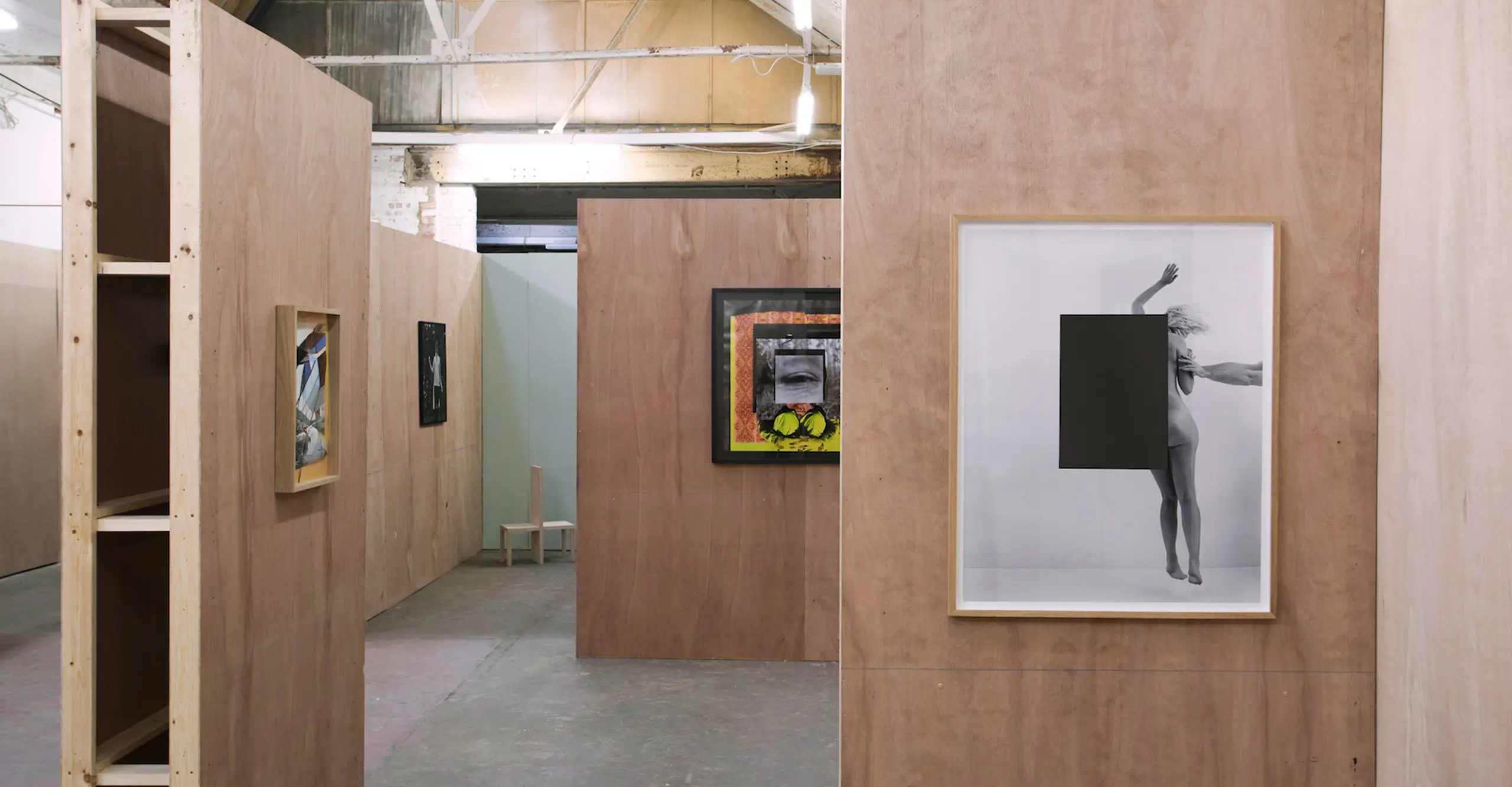 Interior of an exhibition showing photographs on walls that jut out into space.