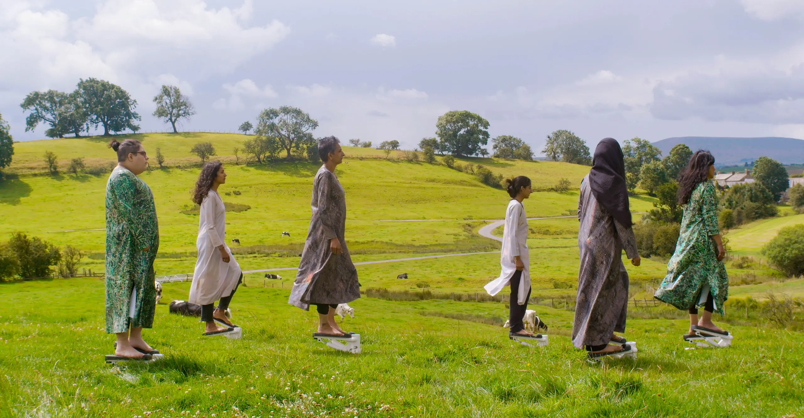 Group of six people standing in an open field facing right