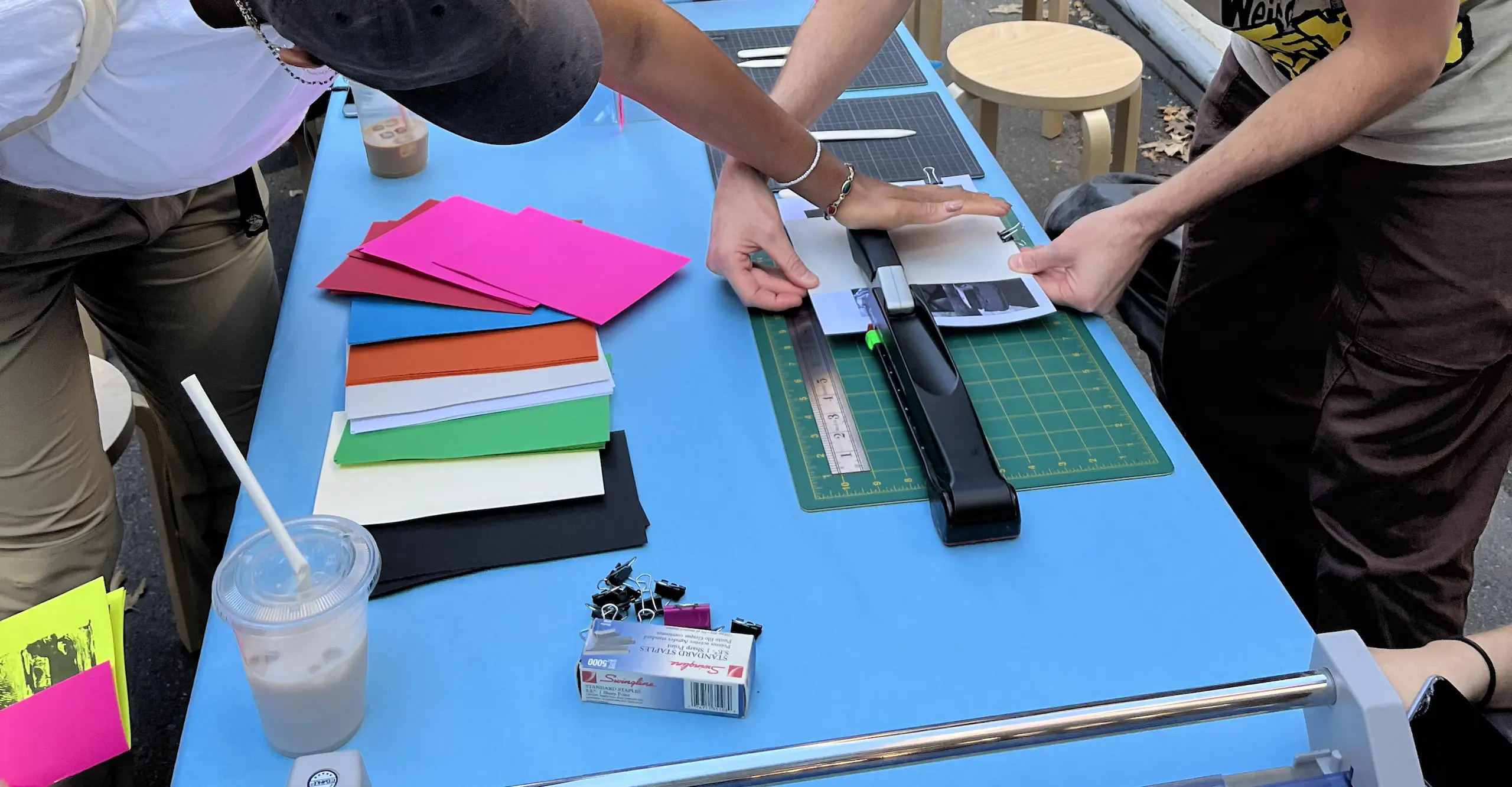 People work at a long table trimming and assembling photographic zines 