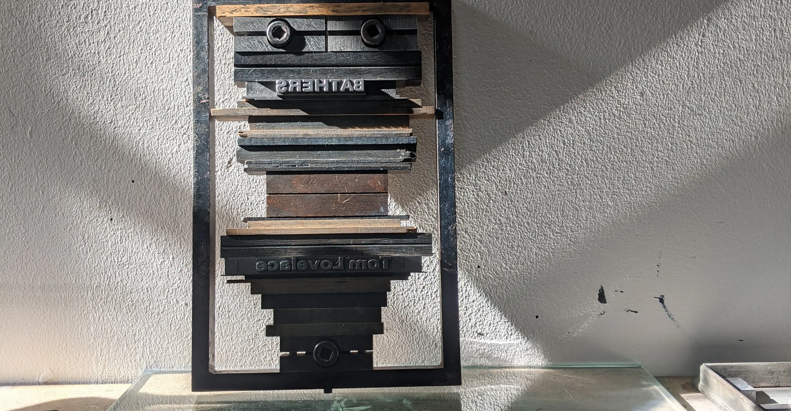 An image by Tom Lovelace of old letterpress machinery, reflected in a sheet of glass on the floor