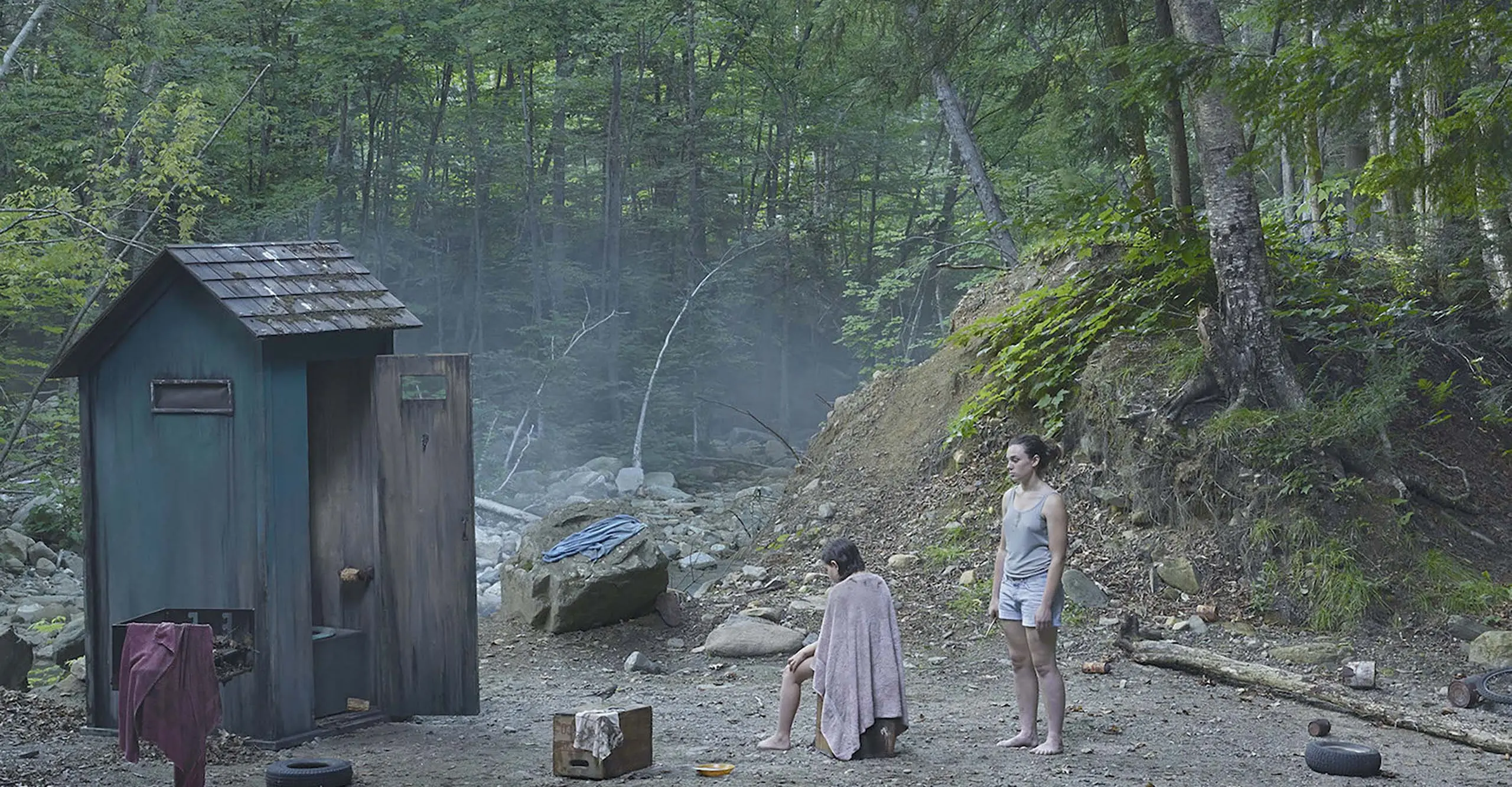 A forest scene with a shed on the left and two figures on the right.