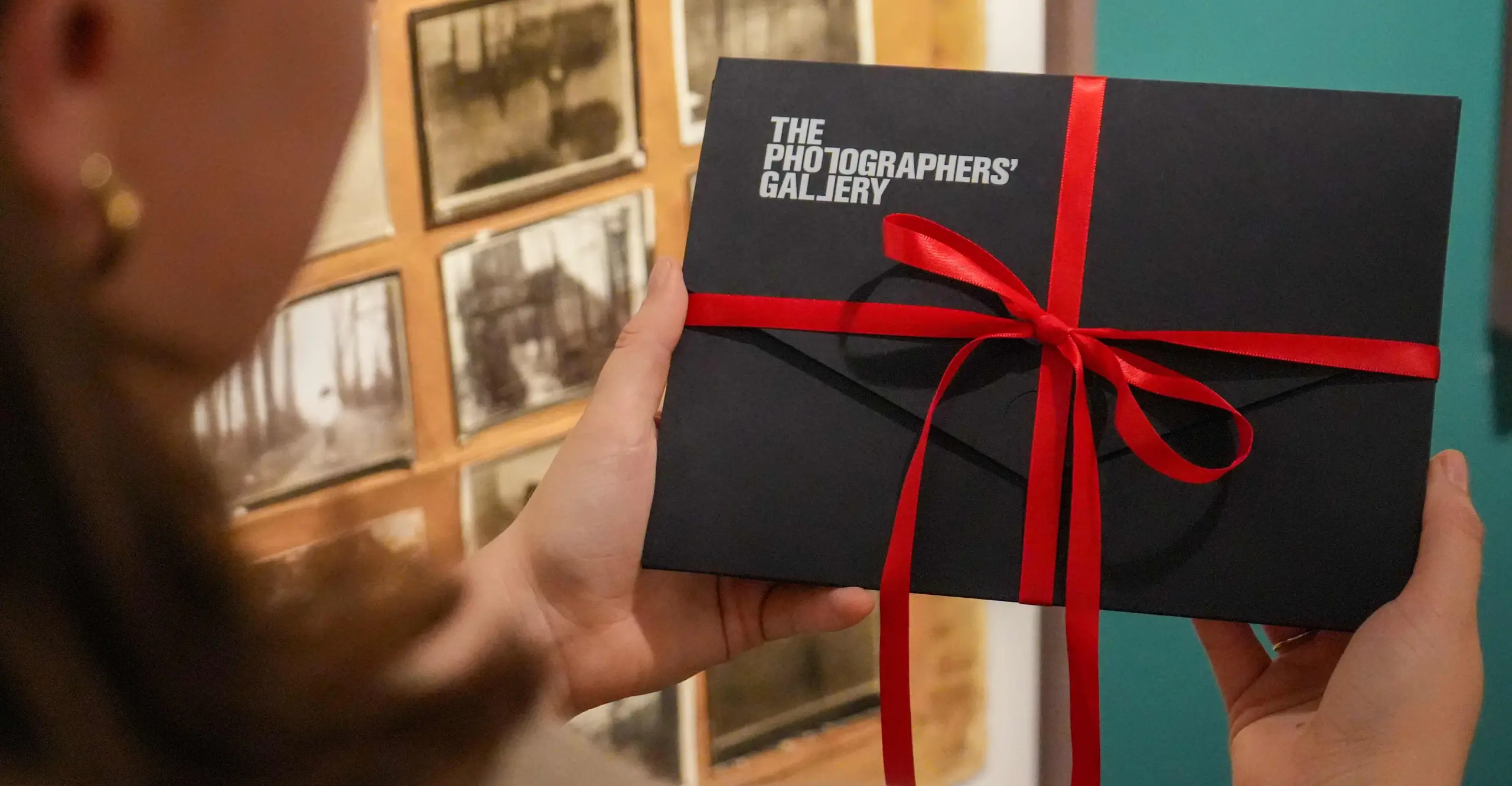 A moving gif of a pair of hands opening a gift membership pack and taking out a membership card.