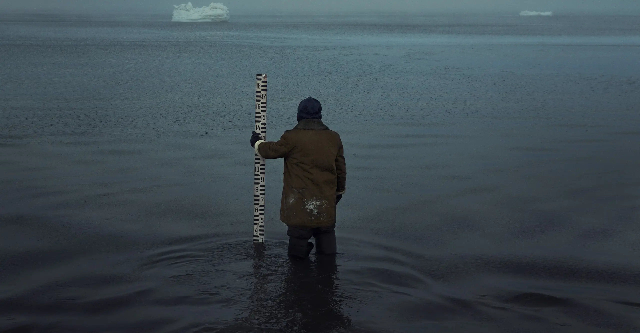 Man looking at iceberg standing in the sea