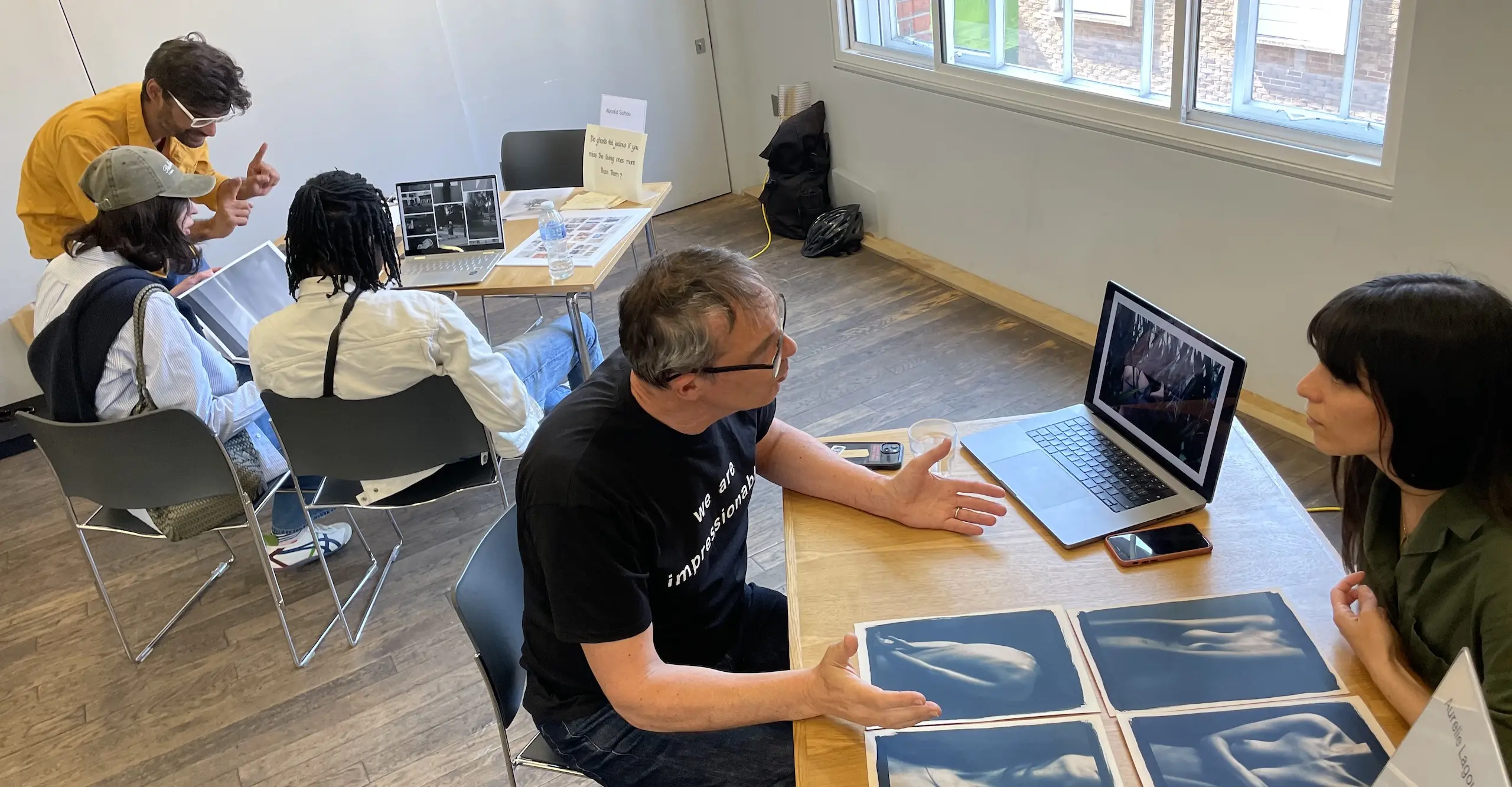 People sit across from each other at two tables with photographs displayed on each.