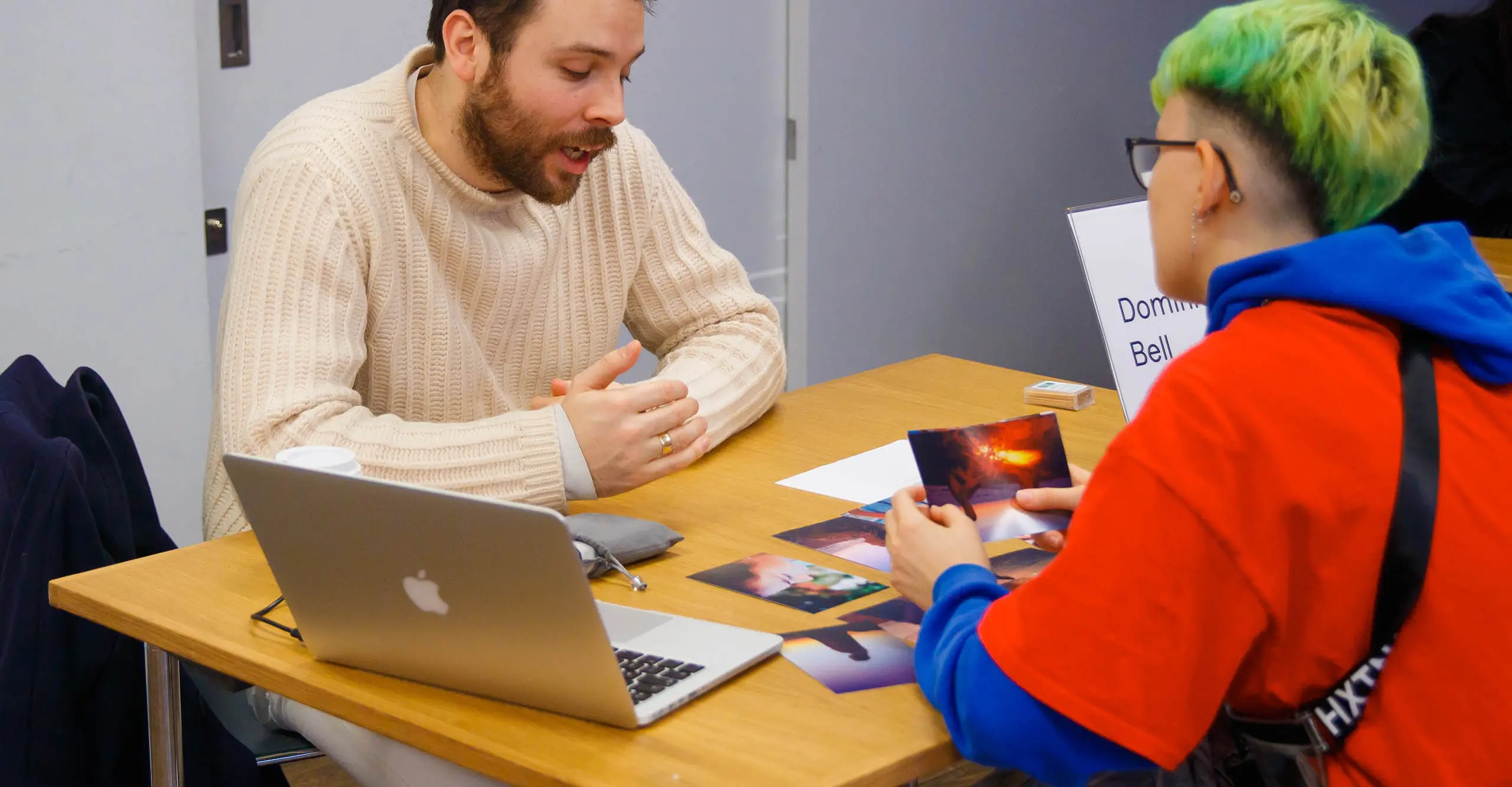 Photograph of two people sat at a table looking through printed photographs.