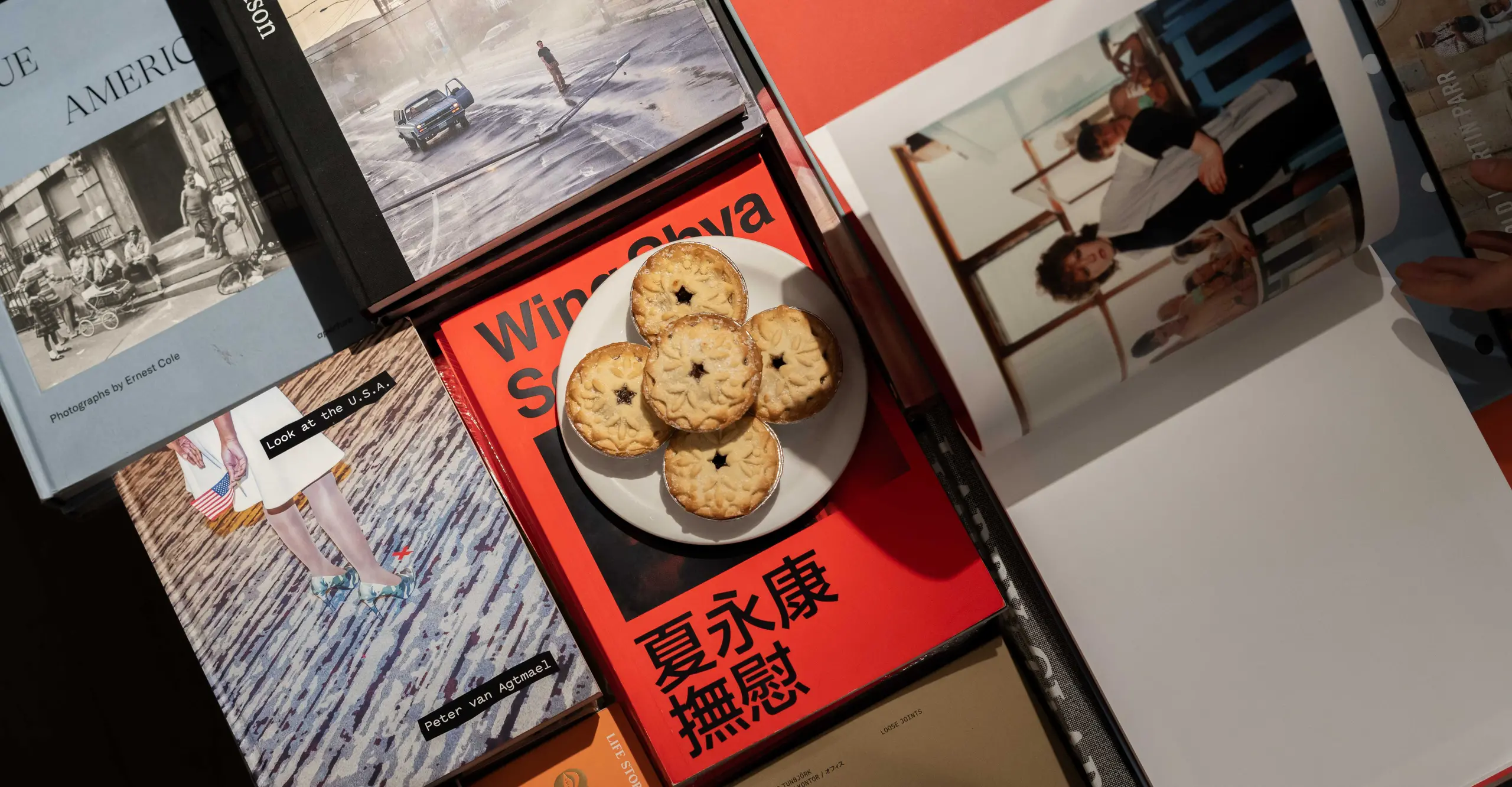 A aerial shot of a plateful of mince pies resting on top of a stack of books.