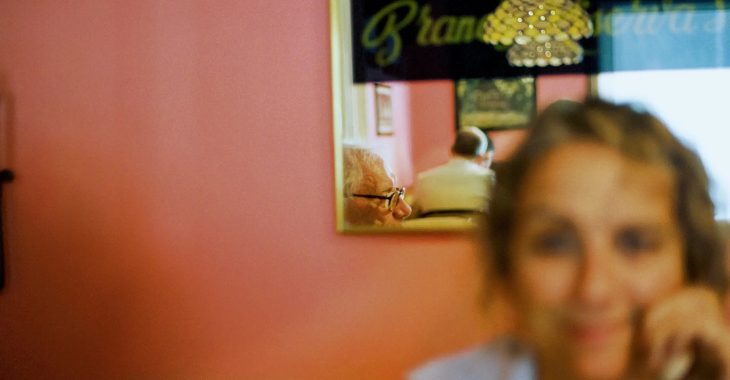 Colour photograph showing someone in the foreground blurred, with the pink background in sharper focus