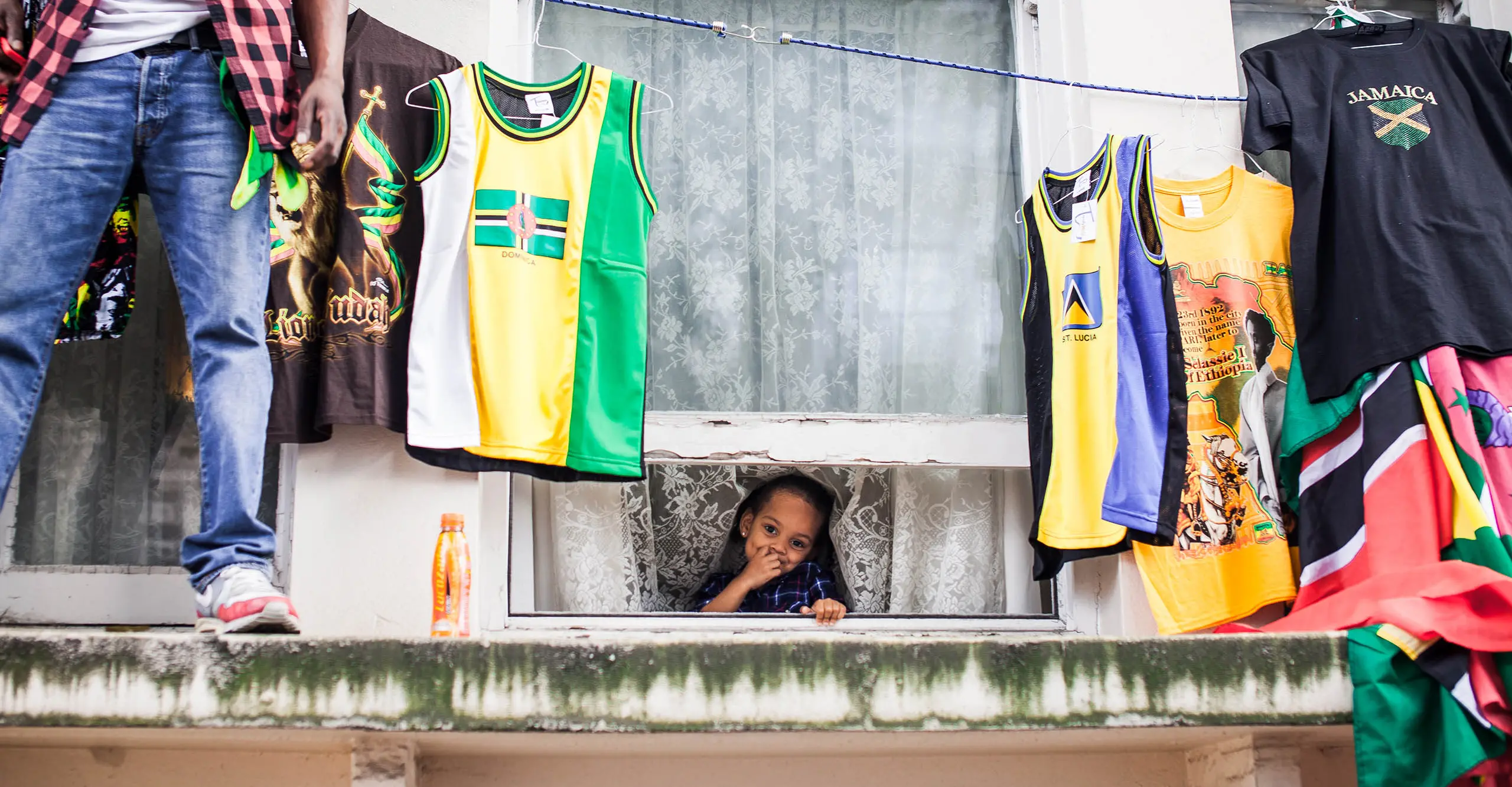 An open window takes up the whole frame and a little girl smiles out of it.