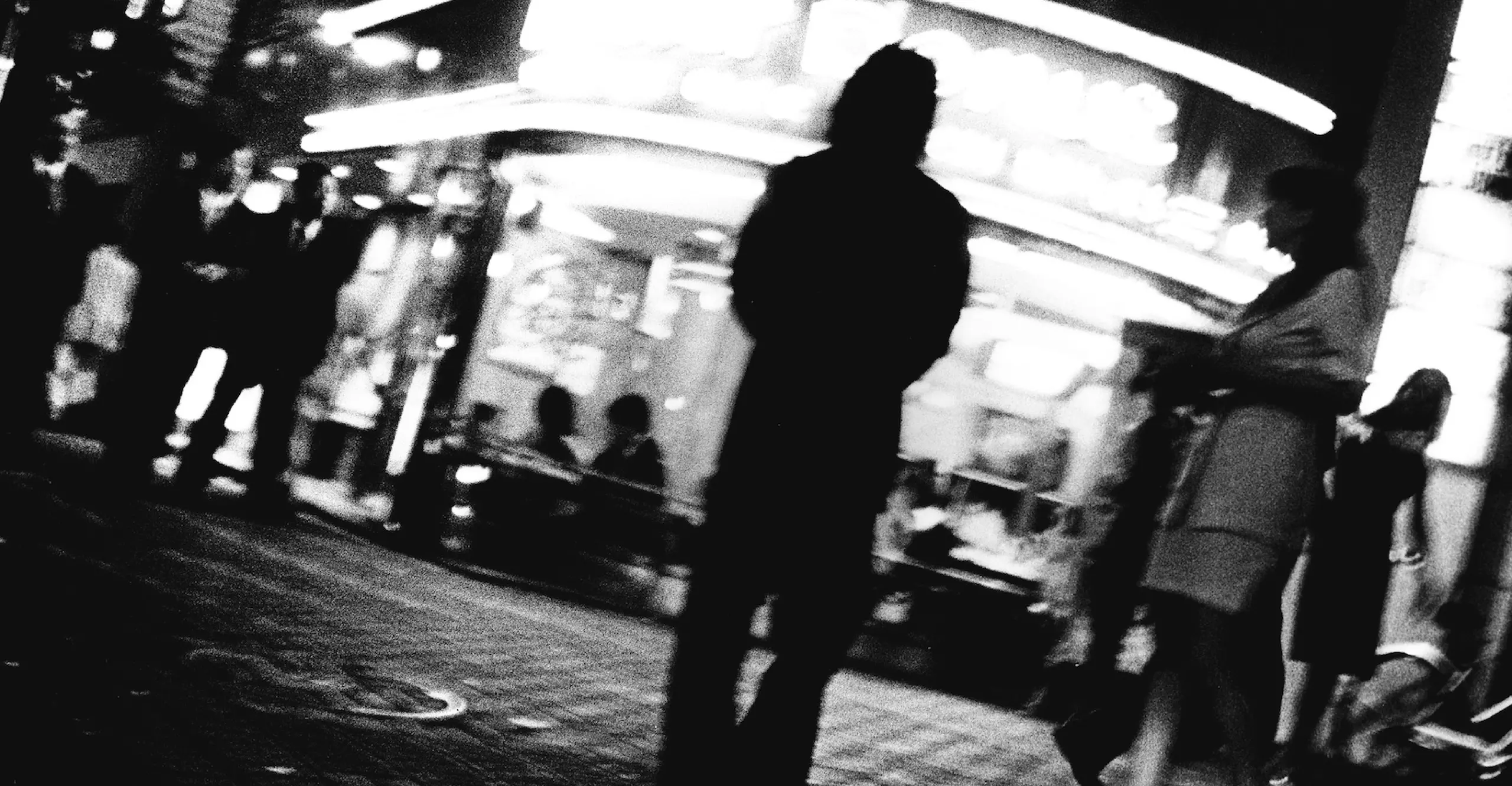 Black and white image of a figure with their back facing in front of a cinema