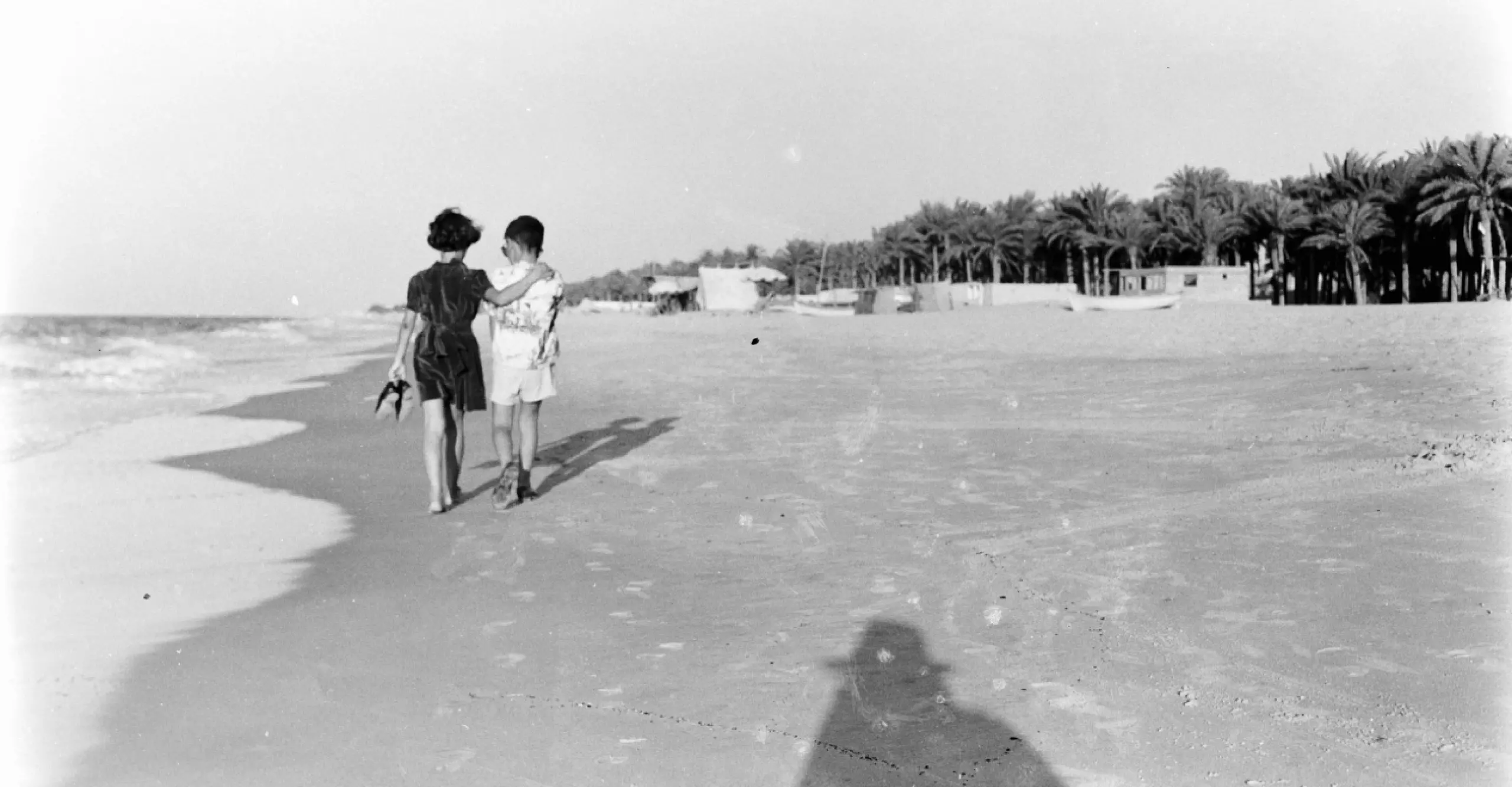 Two figures walking on a beach