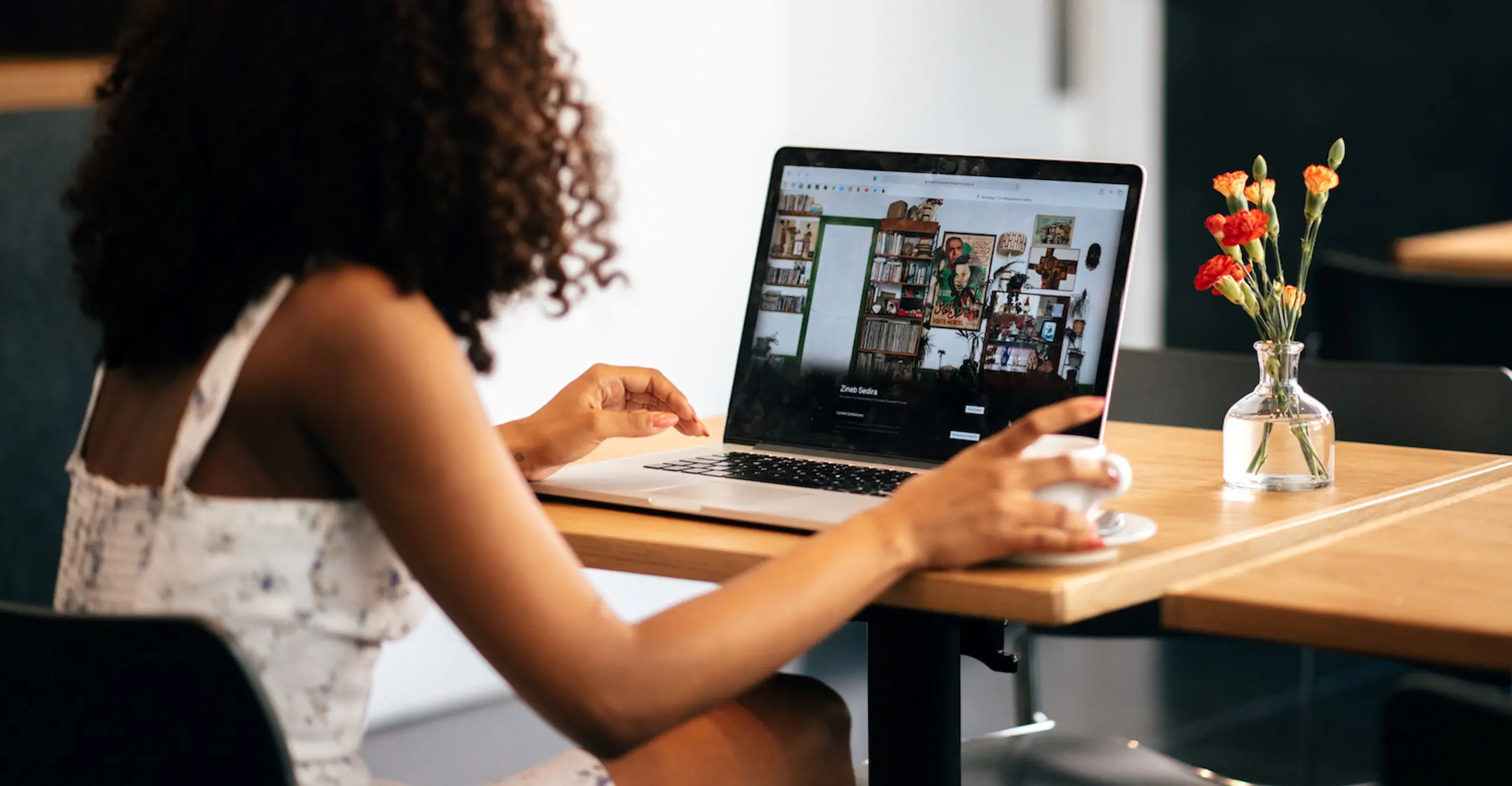 A person sits at a table looking at a laptop screen