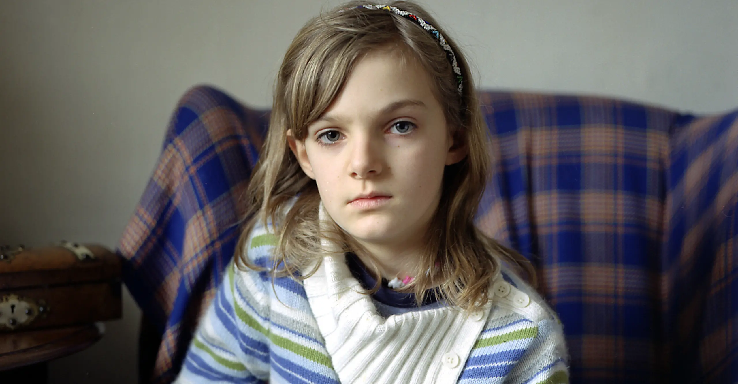 Young girl sits on chair looking into camera