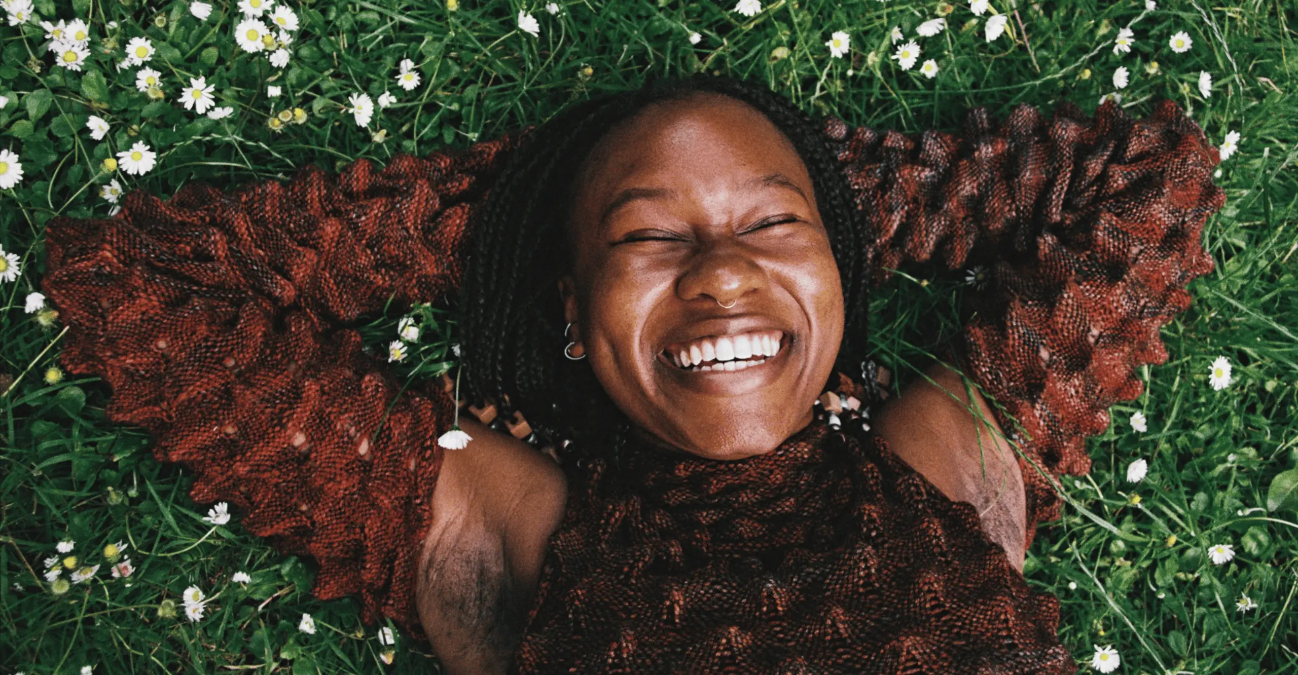 Photograph of woman laying down on grass smiling at the camera.