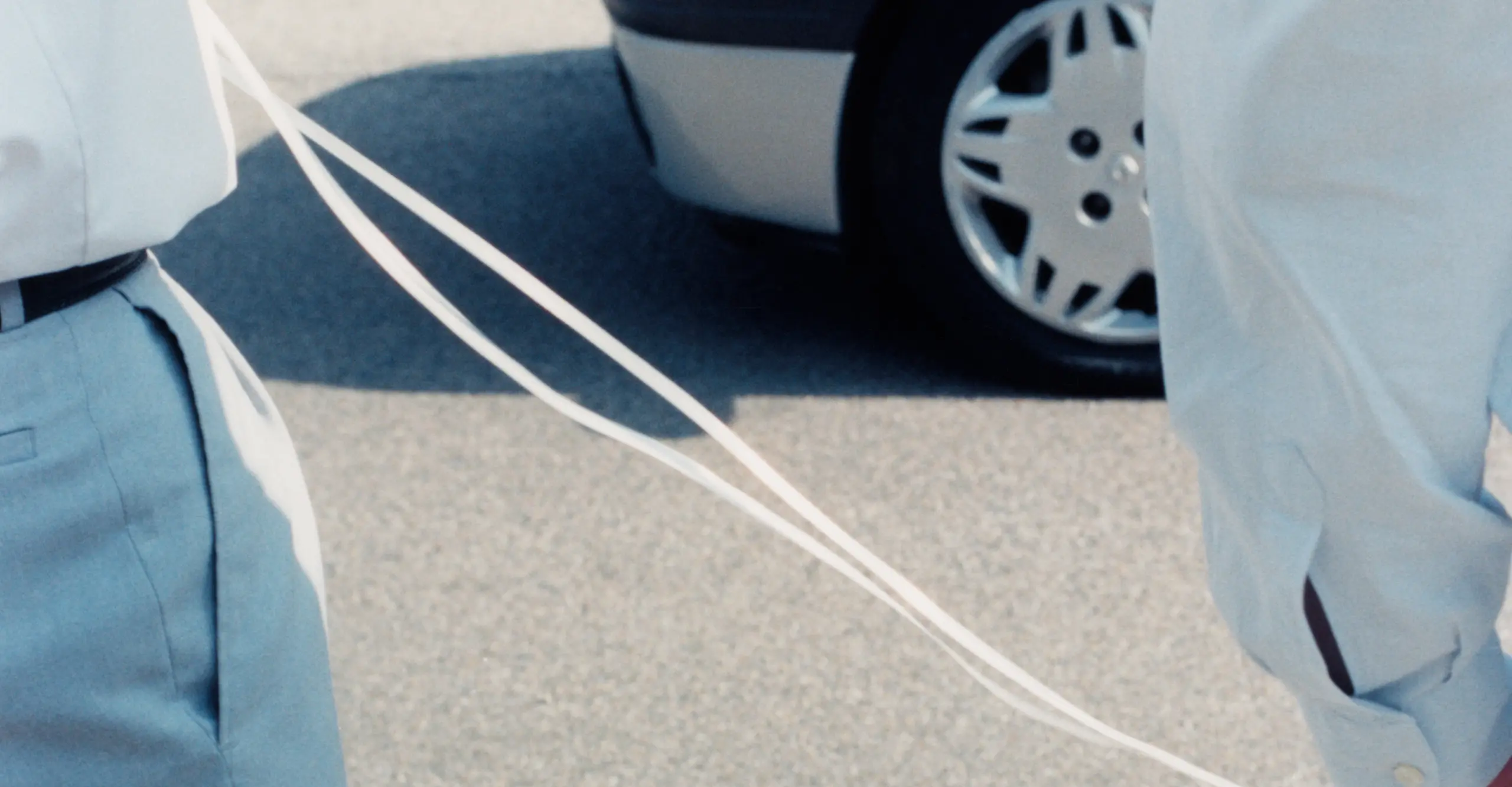 colour photograph of men in a street connected by a white cord