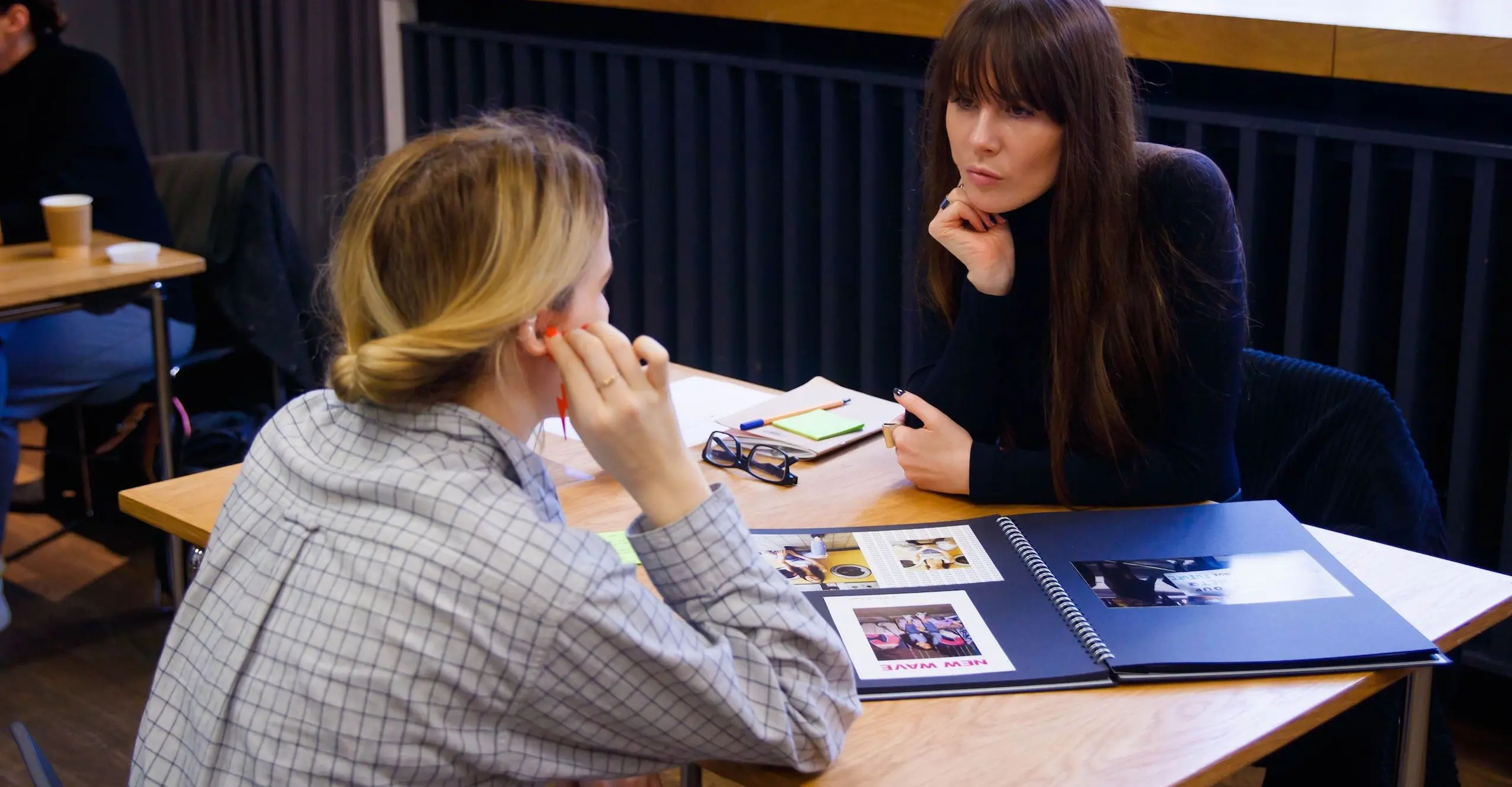 A photo of two people having a conversation about their art work. 