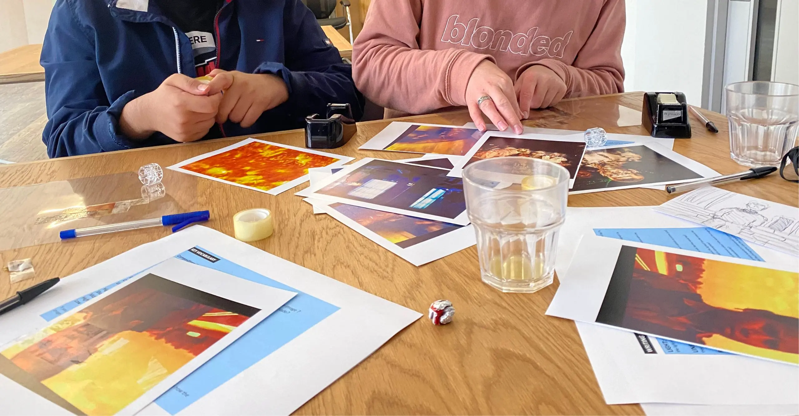 Image of young peoples hands cutting up printed images. 