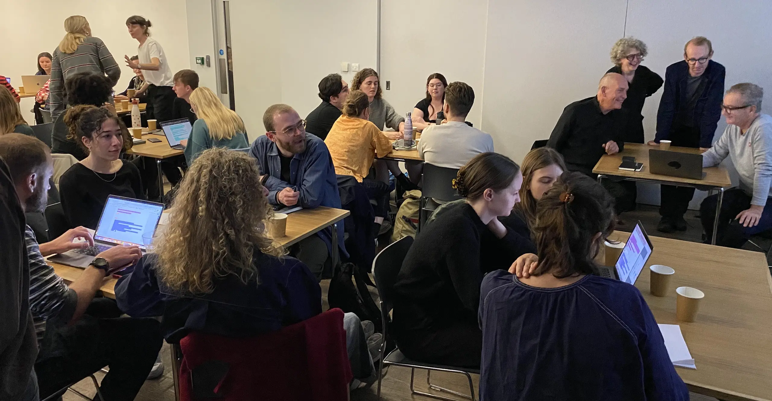 Photograph of a group of people sitting at tables talking together. 