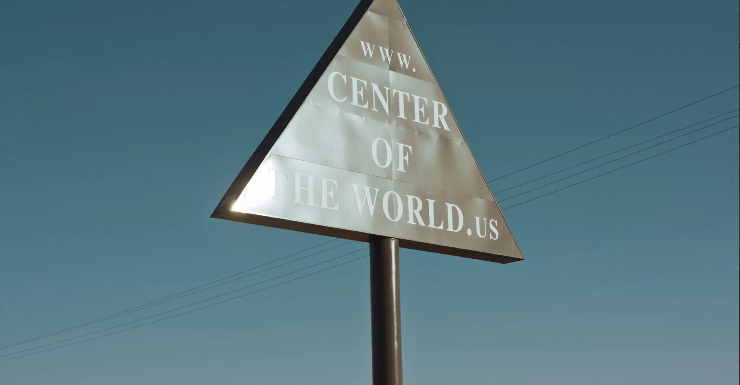 Colour photograph of a a road sign with 'www.centreoftheworld.us' written on it.